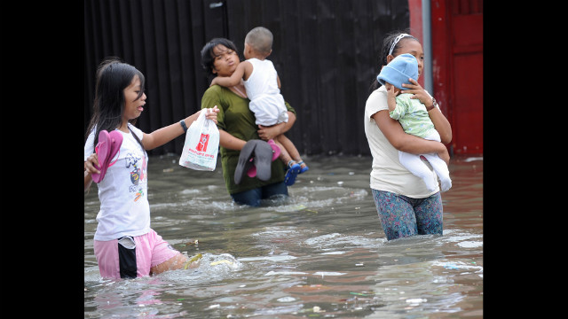 People wade through a flooded street Wednesday in Navotas, a Manila suburb. 