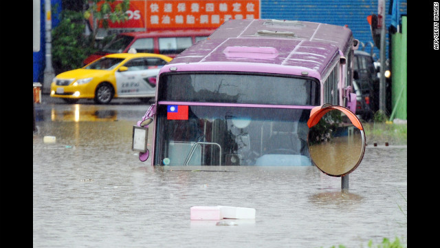 A bus sits half submerged on a flooded road in New Taipei City.