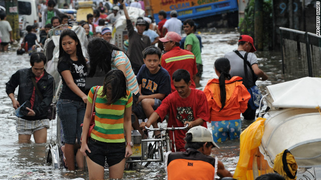 Residents wade through a flooded street in Navotas in suburban Manila. Forty-four evacuation centers have been opened due to flooding. 