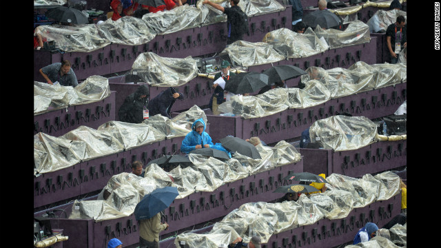 Journalists try to keep their equipment dry with rain covers at the Olympic Stadium.