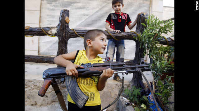 A boy plays with an AK-47 rifle owned by his father in Azaz, some 29 miles north of Aleppo on Friday, August 3. 