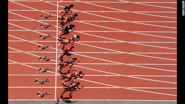 Athletes leave the blocks at the start of the women's 100-meter heat.
