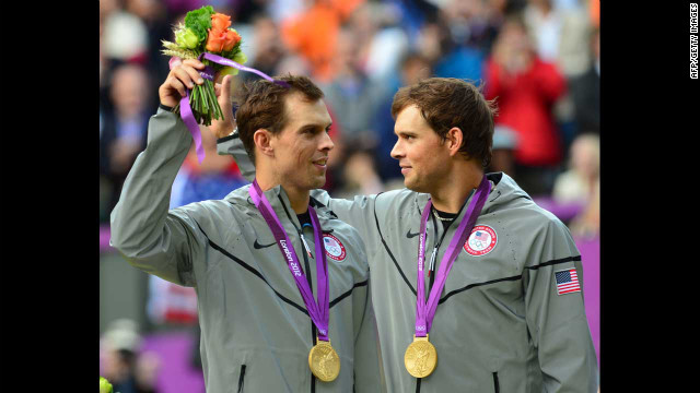 Mike Bryan, left, and Bob Bryan pose on a podium with their gold medals after winning the men's doubles tennis tournament.