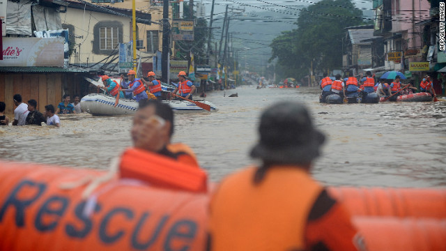 Rescuers maneuver down a flooded street as they evacuate residents in the village of Tumana in suburban Manila on Tuesday, August 7, after torrential rains inundated most of the capital. Authorities have issued a red alert for the metropolitan Manila area. Downpours are expected to continue Wednesday.