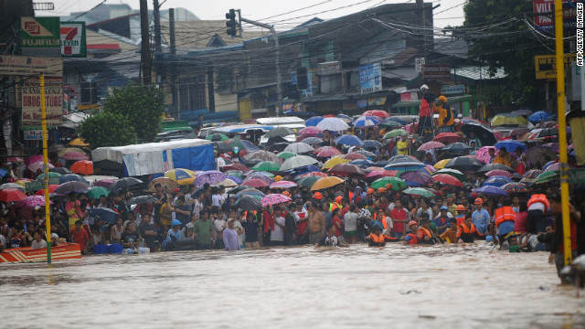 Residents wait for their family members to be rescued at the end of a flooded street in the village of Tumana, a suburb of Manila, Philippines, on Tuesday, August 7. Authorities have issued a red alert for the metropolitan Manila area. Downpours are expected to continue Wednesday.