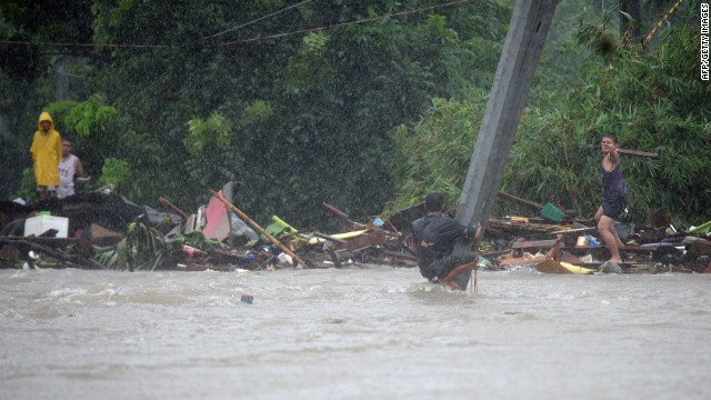 A man clutches a pole in flood waters after a river overflowed following torrential rain in Manila.