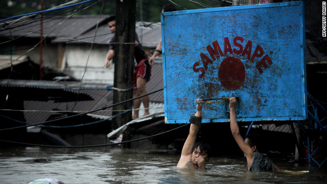 Two men hang onto a basketball hoop in deep floodwaters in Manila.