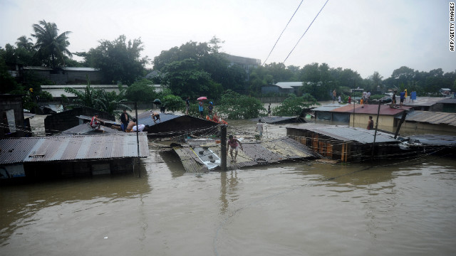 Residents seek shelter on the roofs of their homes as floodwaters continue to rise in Manila.