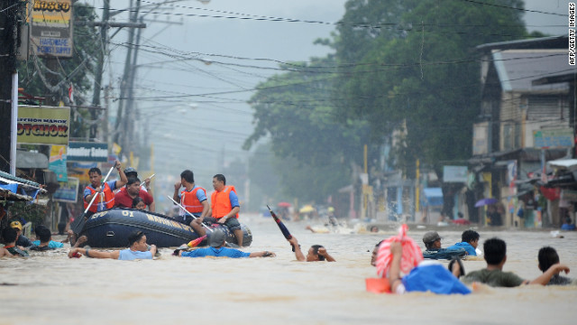 Residents wait on the roofs of buildings as rescuers make their way down a flooded street in Tumana.