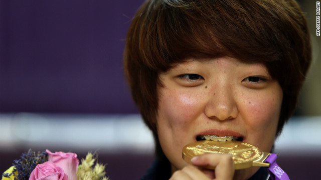 South Korea's Kim Jang-mi bites her gold medal on the podium after victory in the women's 25-meter pistol final.