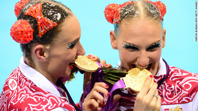 Russia's Natalia Ishchenko and Svetlana Romashina bite their medals after winning gold in the duets free routine final during the synchronized swimming competition at the London 2012 Olympic Games.