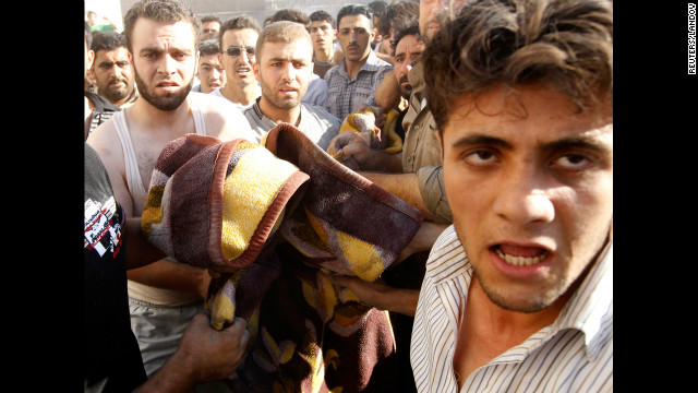 Men carry the body of a boy killed in an airstrike in the village of Tel Rafat.