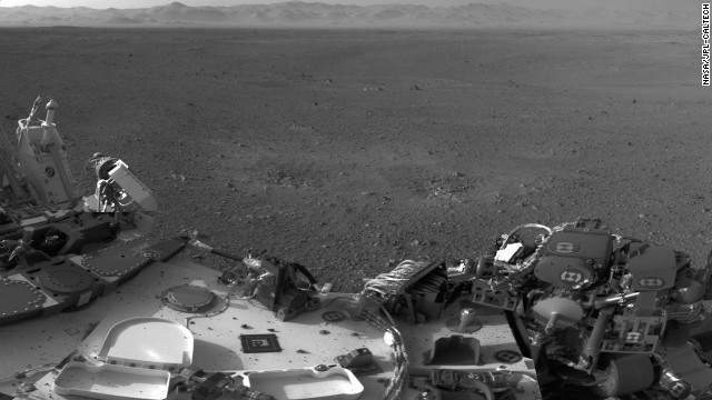 Two blast marks from the descent stage's rockets can be seen in the center of this image. Also seen is Curiosity's left side. This picture is a mosiac of images taken by the rover's naviagtion cameras.