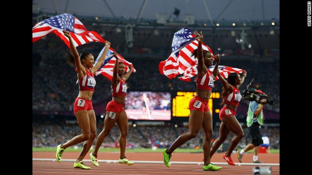 The U.S. women's 4x100-meter relay team wave the flag to celebrate their world record and gold medal winning victory.