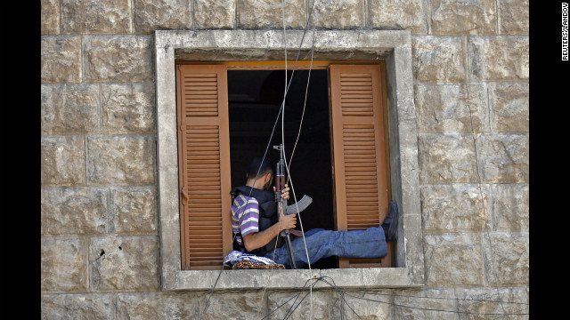 A Free Syrian Army fighter sits on a window sill as he holds an AK-47 rifle in central Aleppo.