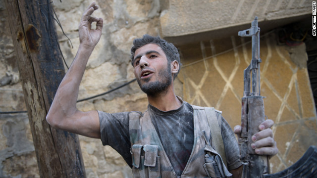 A rebel fighter gestures toward others after emerging from a shelled building during fighting Monday with government forces.