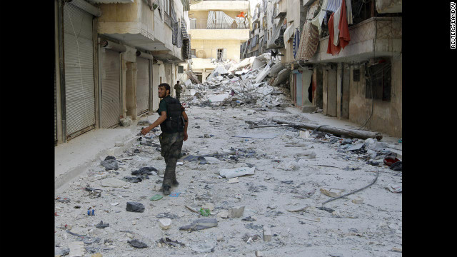 Free Syrian Army fighters walk down a debris-covered street Monday in central Aleppo's Salaheddine neighborhood.