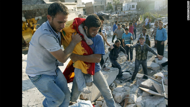 A man carries the body of a boy after a Syrian Air Force strike on Azaz, some 29 miles north of Aleppo.