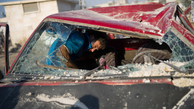 A man removes his belongings from his destroyed car at the airstrike site.