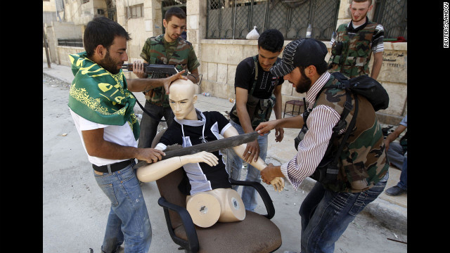 Free Syrian Army fighters dress a mannequin to look like a fighter to draw gunfire away from them Friday in Aleppo.