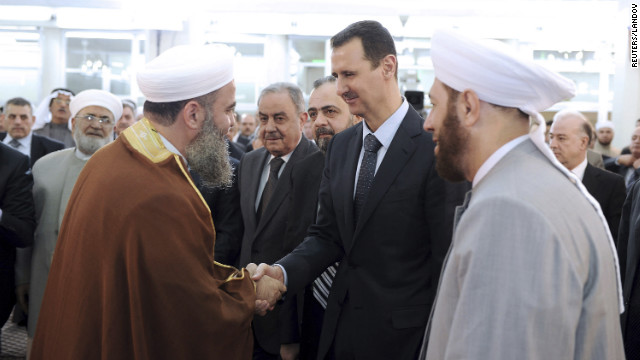 In this image provided by Syria's national news agency, SANA, President Bashar al-Assad, center, is greeted by a cleric while attending Eid al-Fitr prayers at al-Hamad mosque in Damascus on Sunday, August 19.