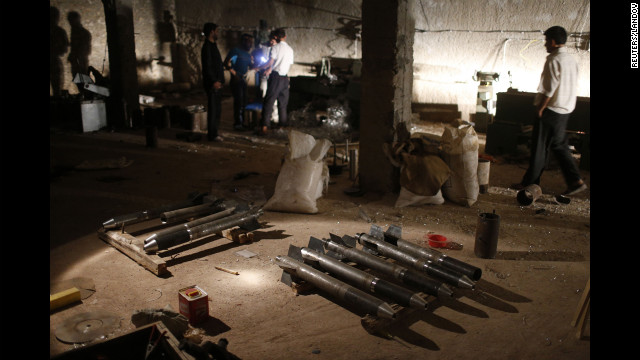 Syrian rebel fighters stand around a cache of homemade missiles which they say they will use on forces loyal to president Bashar al-Assad in Aleppo on August 21.