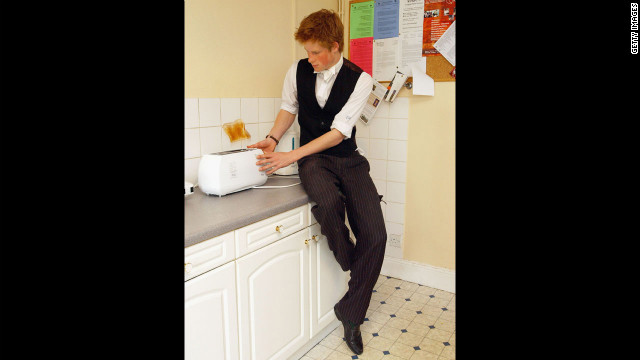 The youngest son of the Prince of Wales, Prince Harry makes a slice of toast in his house kitchen situated in the house library, which is the preserve of the senior House prefects, in March 2003 at Eton College.
