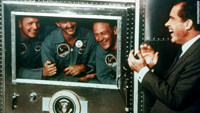 President Richard Nixon applauds the Apollo 11 astronauts, who were confined in a quarantine trailer after their flight, on July 25, 1969.