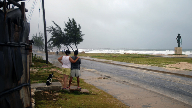 A couple watch as waves and strong winds from Tropical Storm Isaac, which passed by Cuba on Sunday, batter the shore in Gibara, Cuba, on Saturday, August 25.