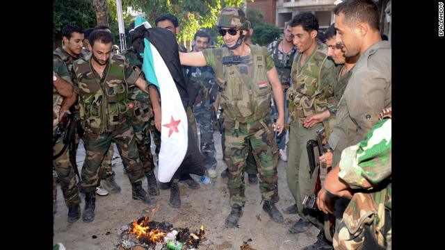 A handout picture released by SANA shows army soldiers burning a revolution flag in Aleppo.
