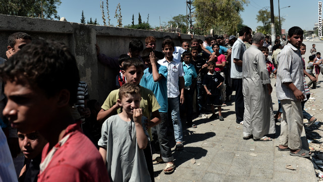 Residents line up along a street in Aleppo as they wait to receive free bread.