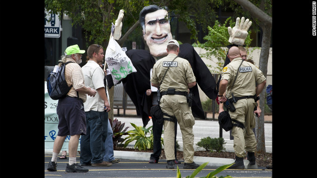 Police officers question protesters carrying an effigy of Republican Party presidential candidate Mitt Romney during a demonstration in downtown Tampa.