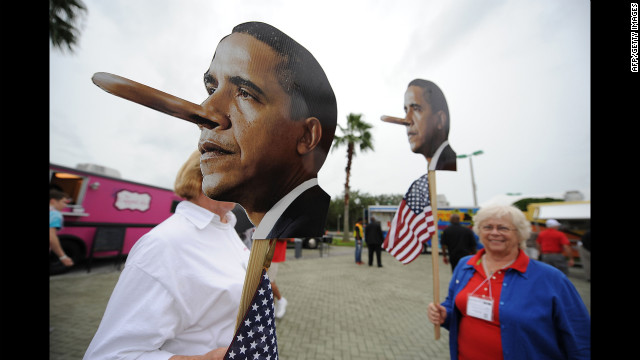 Activists hold signs mocking President Barack Obama at the Tea Party Unity Rally at The River at Tampa Bay Church.