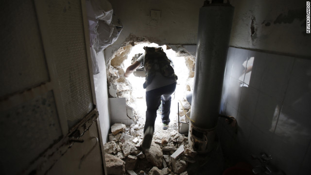 A Free Syrian Army fighter walks through a hole in a damaged house on his way to the El Amreeyeh neighborhood frontline during clashes with government forces in Aleppo.