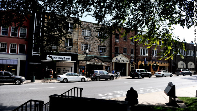 A man sits on College Avenue, the main drag that is lined by shops and restaurants. 