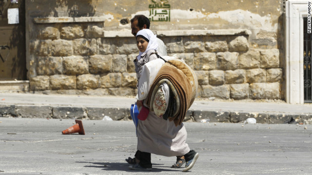 Civilians carry their belongings and flee the El Edaa district after an airstrike.
