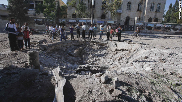 Civilians stand near a bomb crater after a Syrian air force fighter jet dropped a bomb on Wednesday, September 5, in Azaz, a town north of Aleppo.