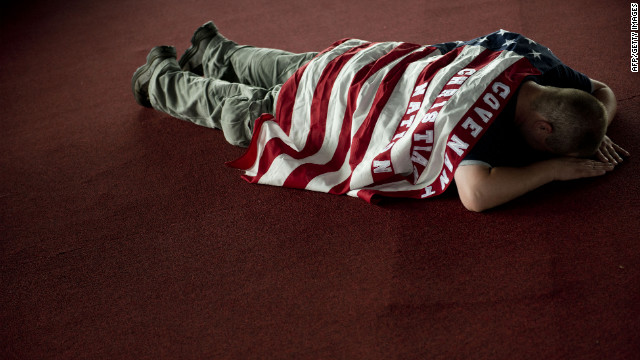 Nathan Conley, draped in an American flag with the phrase "Covenant Christian Nation," prays during a prayer service at the Verizon Wireless Amphitheatre in Charlotte on Sunday. 