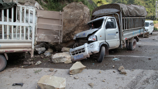 Damaged vehicles sit at a roadside in Yiliang.