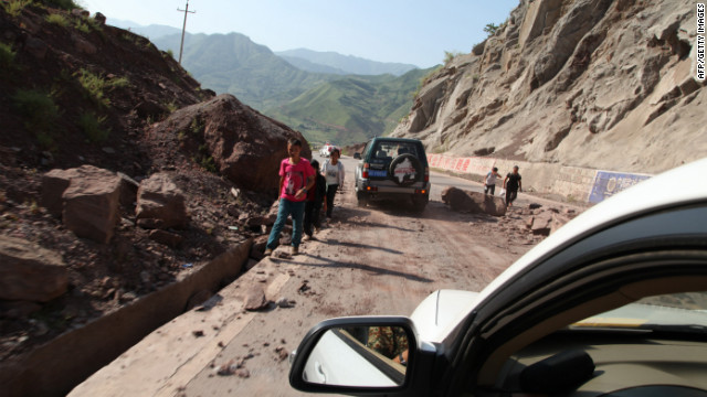 Vehicles make their way slowly along the road after rocks tumbled in Yiliang.