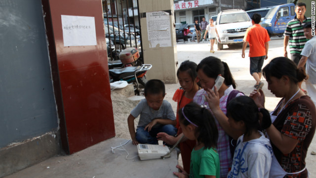 Survivors gather to make phone calls by a street in Yiliang.