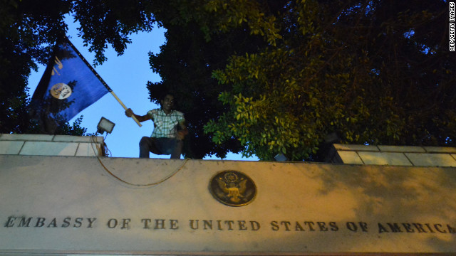 An Egyptian protester waves a black flag inscribed with the Muslim profession of faith -- "There is no God but God, and Mohammed is the prophet of God" -- as he stands above the door of the U.S. Embassy.