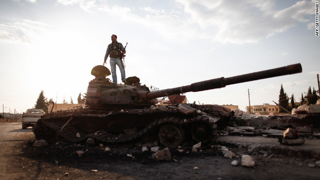 An armed fighter of the Free Syrian Army stands atop a destroyed Syrian army tank to have his picture taken by a passer-by in the northern Syrian town of Azaz, some 47 kilometers north of Aleppo, on Monday.