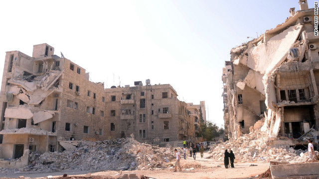 People walk past a row of destroyed buildings near the Al-Hayat Hospital in Aleppo on Monday.