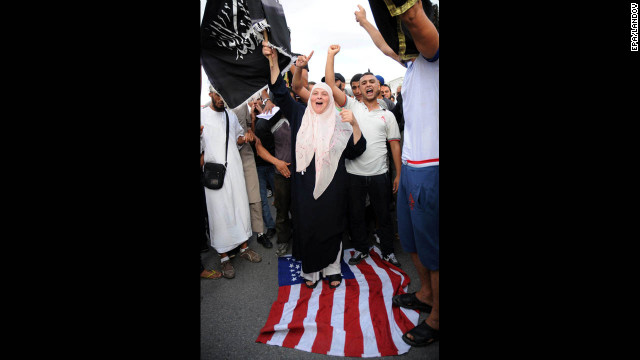 A demonstrator walks on a U.S. flag during a Wednesday's demonstration at the U.S. Embassy in Tunis.