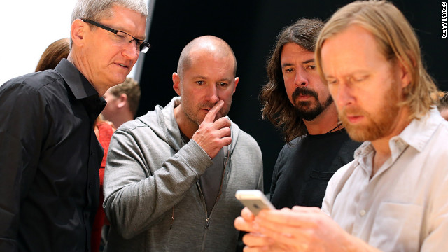 Apple CEO Tim Cook, left; Jonathan Ive, senior vice president of industrial design; and Dave Grohl of the Foo Fighters watch Foo Figters' bassist, Nate Mendel, handle the iPhone 5.