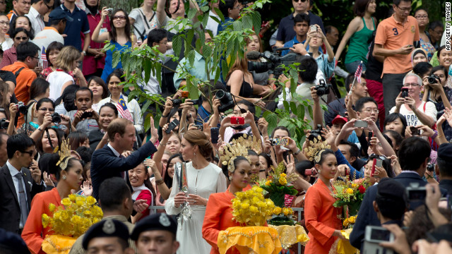 A crowd takes photos of Prince William and Catherine, Duchess of Cambridge, as they walk in the KLCC gardens in Kuala Lumpur on Friday.