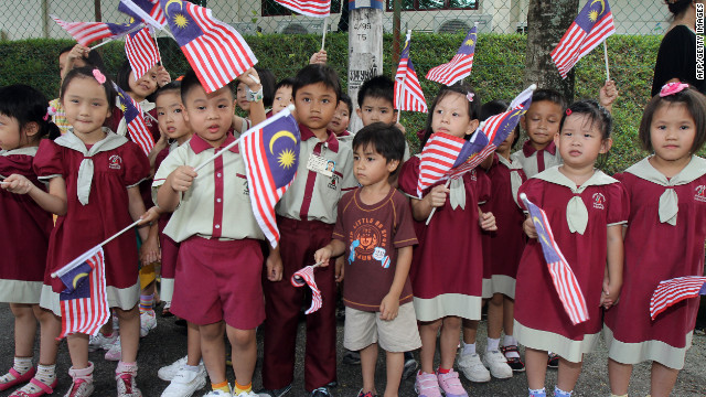 Schoolchildren wave Malaysia national flags as Britain's Prince William and his wife Catherine, the Duchess of Cambridge, arrive at the Hospis Malaysia in Kuala Lumpur on September 13, 2012.