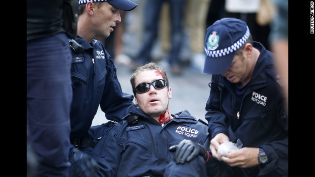  A policeman, injured by protesters, is assisted by colleagues in central Sydney on Saturday.