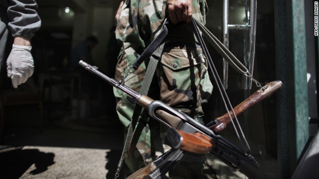 A Syrian rebel holds AK-47 rifles belonging to wounded comrades at the entrance to an Aleppo hospital on Tuesday.